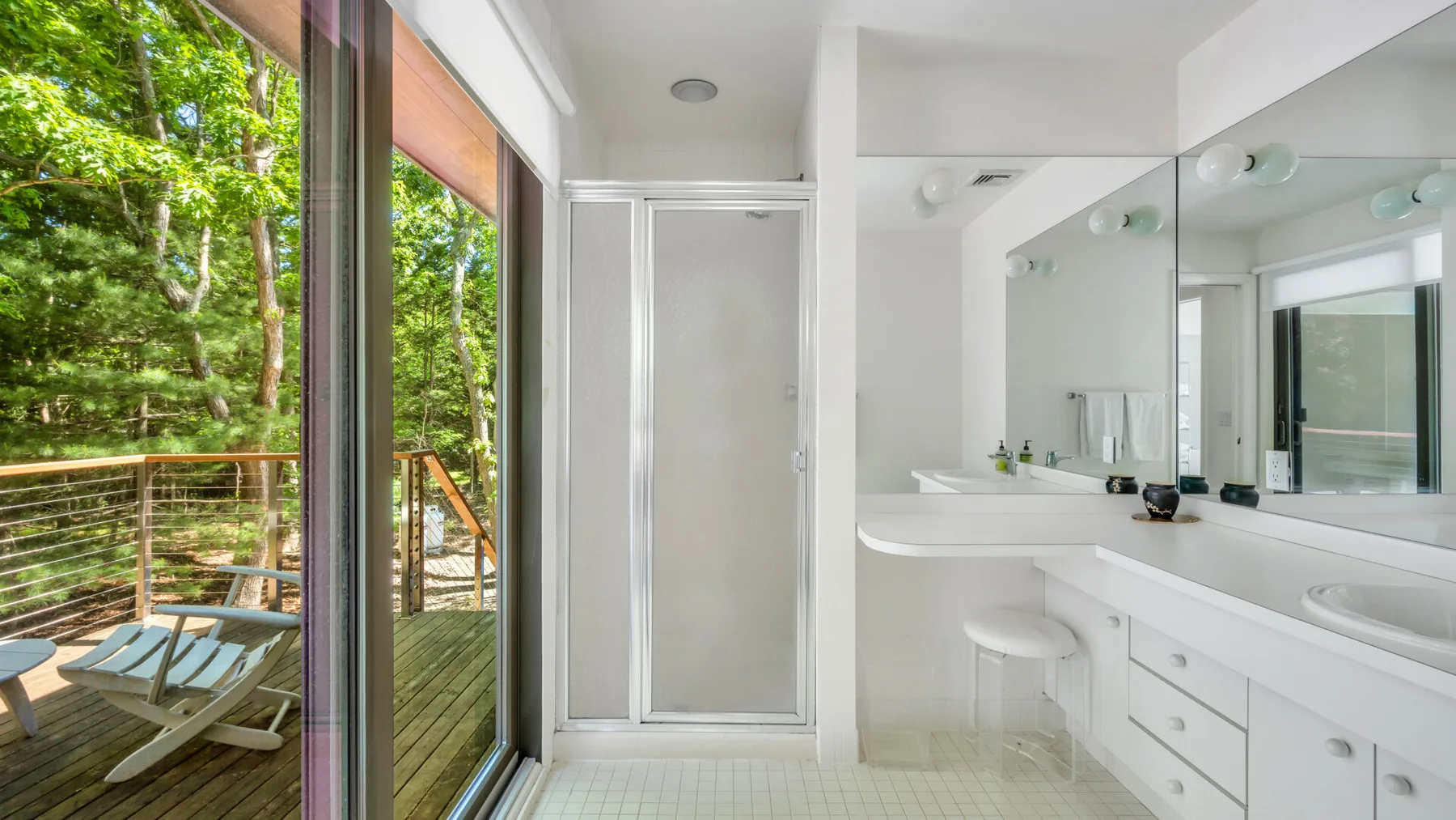 Un baño luminoso con un largo lavabo junto a ventanales.