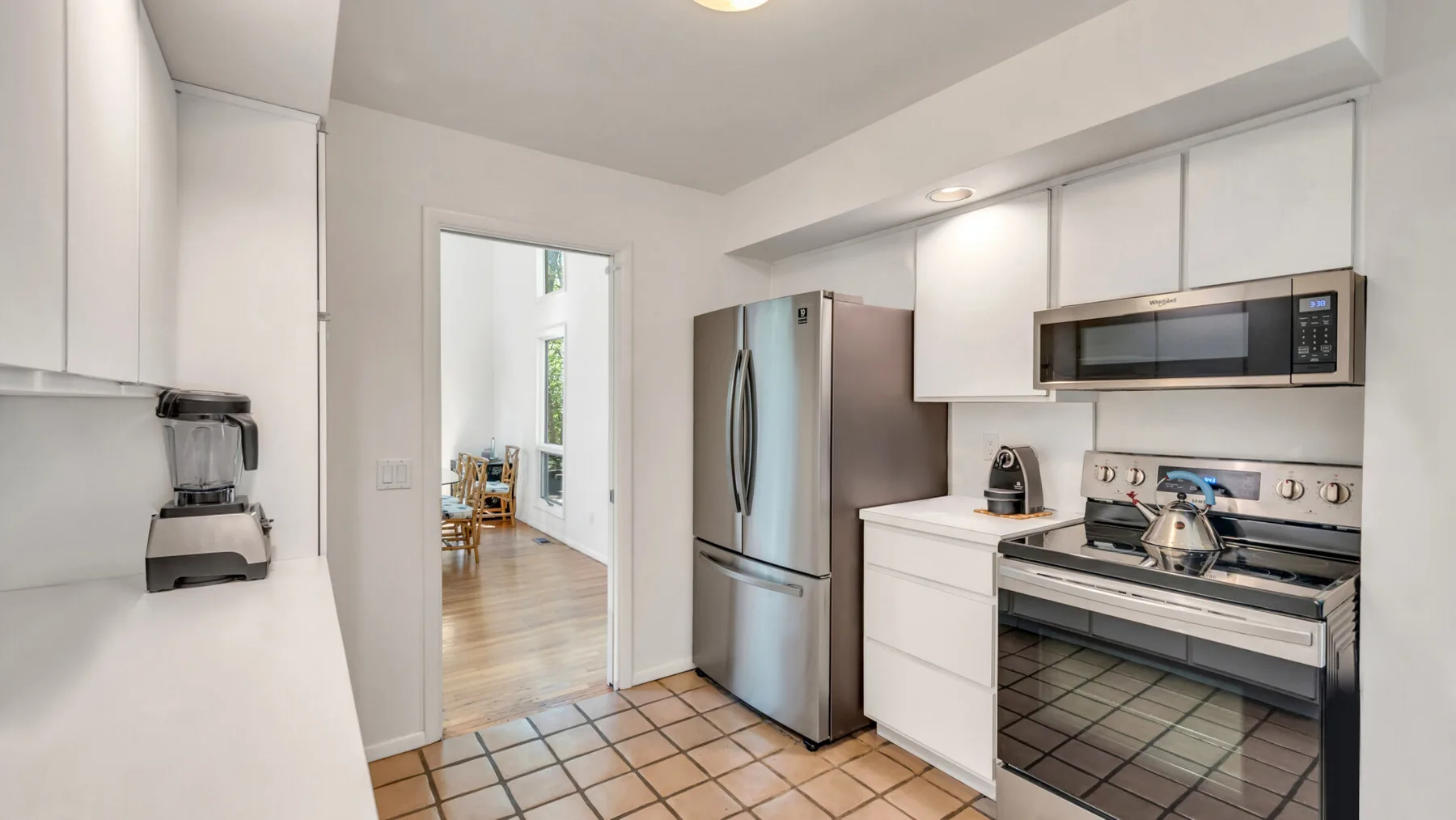 Una cocina luminosa con gabinetes blancos, un refrigerador y una estufa.