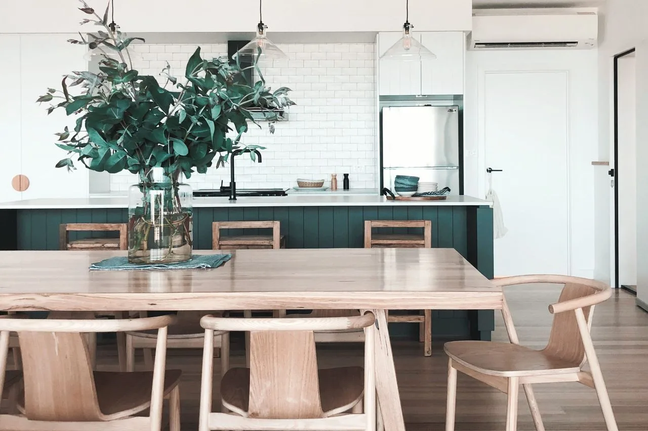 A dining area with a wooden table and chairs beside a kitchen island.