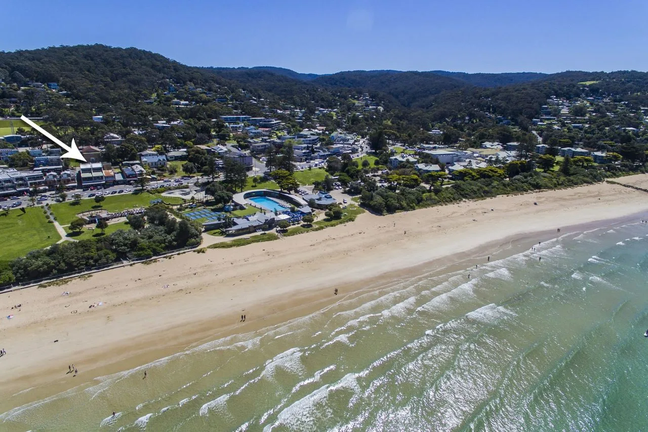 Aerial view of a sandy beach, ocean waves, and a coastal town.