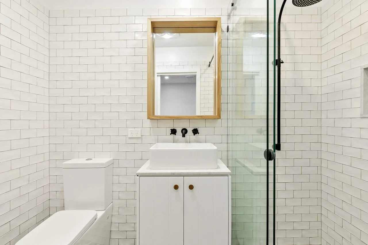 A tiled bathroom with a sink, mirror, and glass shower.