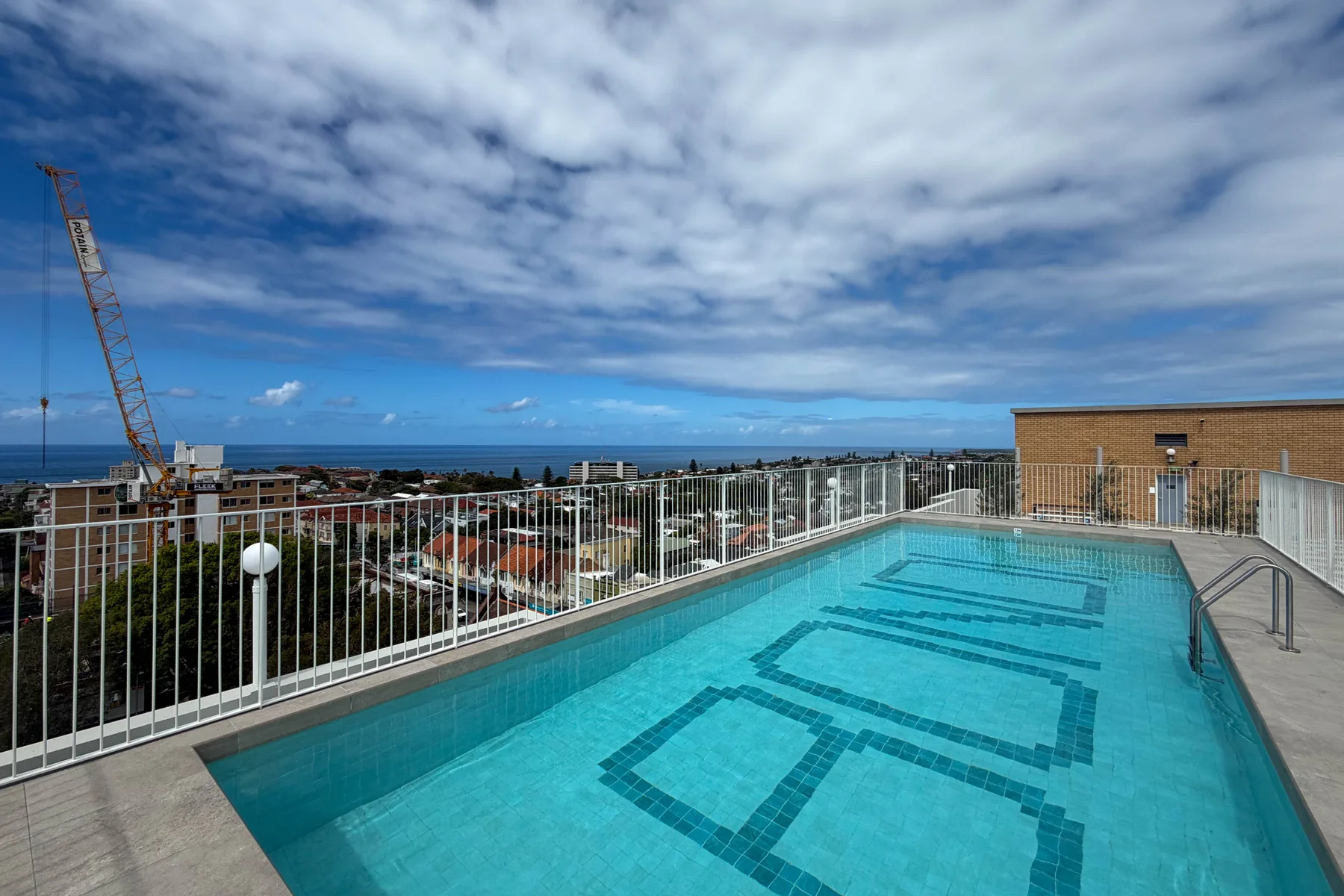 La terraza de la azotea cuenta con una piscina elevada y amplias vistas de la ciudad y del océano al fondo.