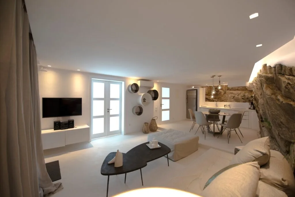 Sala de estar y comedor de planta abierta con televisor y mesa.