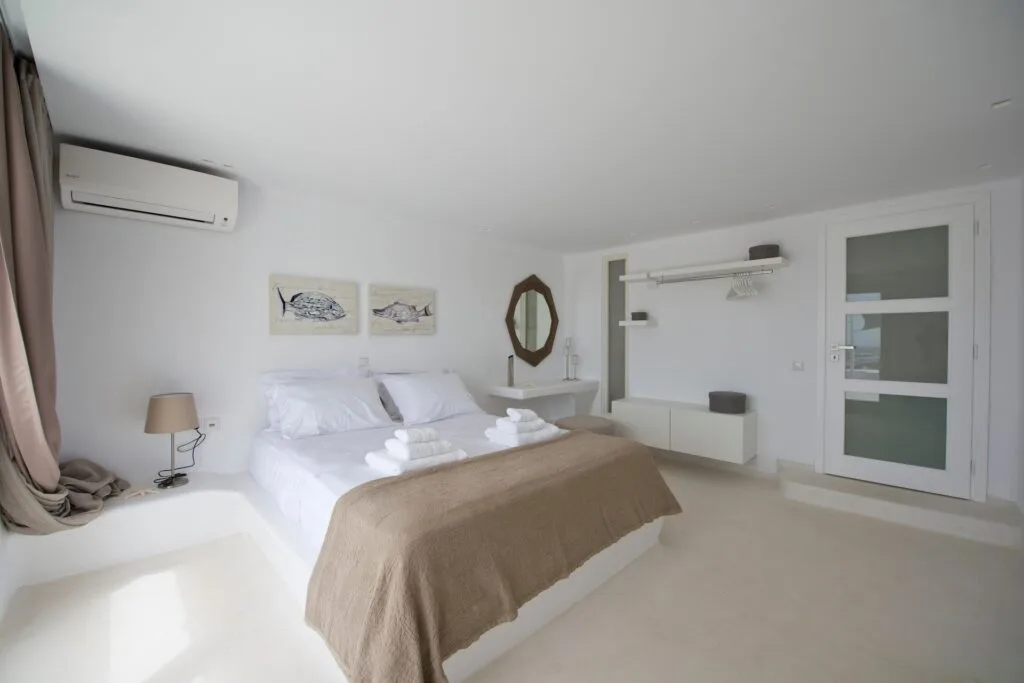 Un dormitorio luminoso con una cama bien hecha y una puerta con paneles de vidrio.