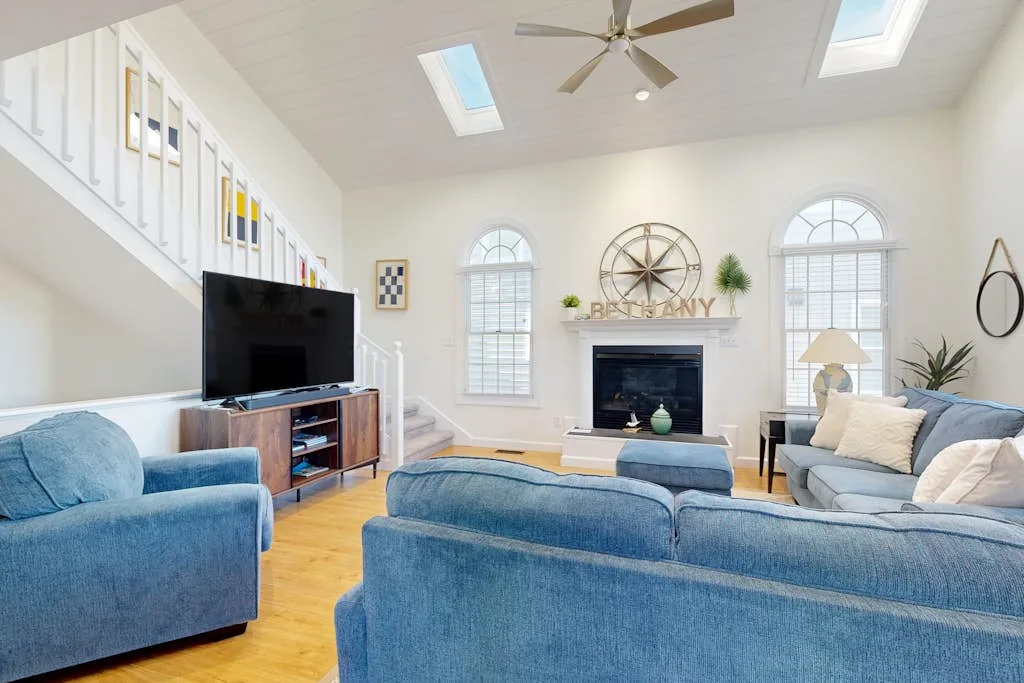 A bright living room with blue seating, a television, and a fireplace.