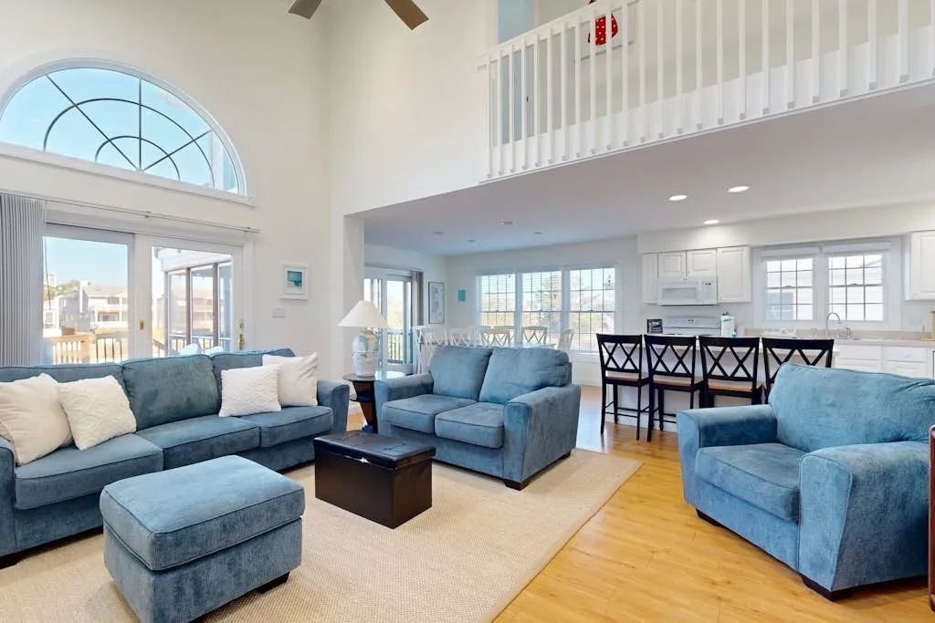A bright open living and dining area with blue seating and large windows.