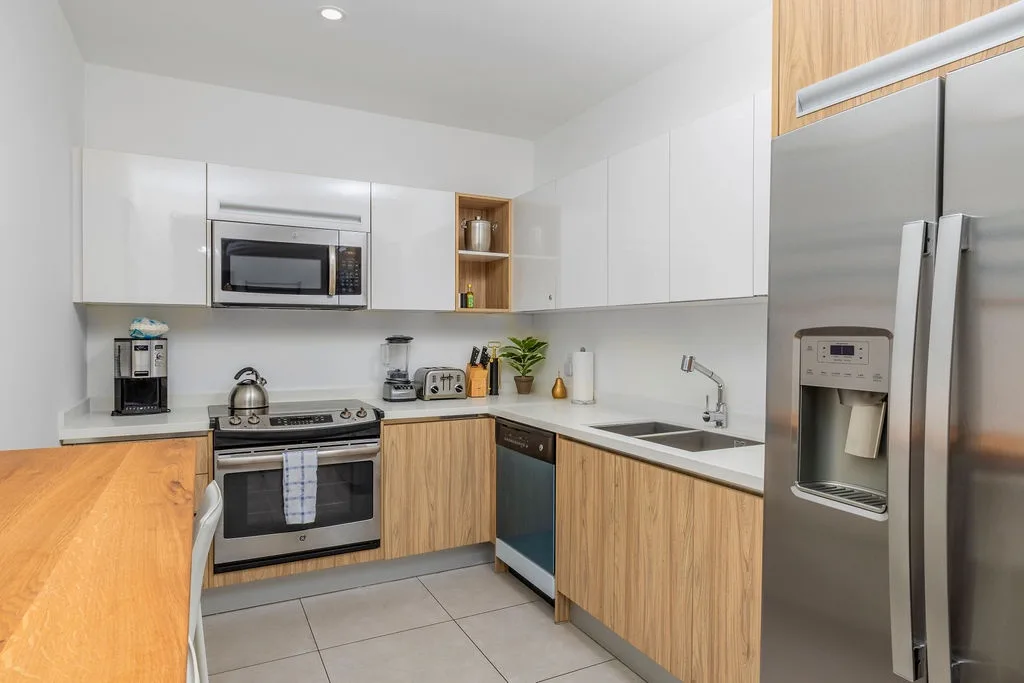 Your modern kitchen features stainless steel appliances, sleek white countertops, and warm wood cabinetry for all your culinary adventures.