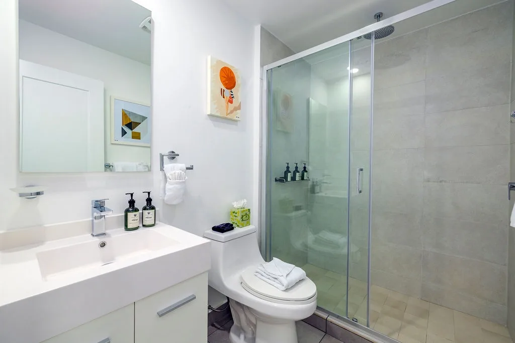 Step into your modern bathroom with a sleek glass-enclosed shower, plush towels, and a vanity stocked with premium amenities—your private retreat awaits.