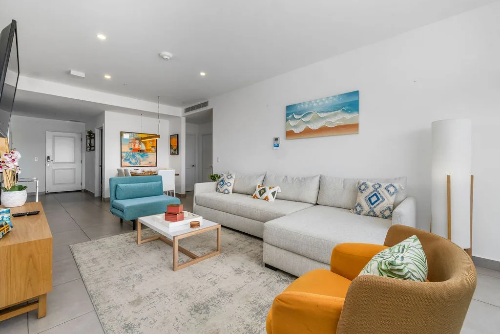 Sink into the plush sofa and unwind in your bright, coastal-inspired living space, where pops of turquoise and orange echo the beachside palette and invite you to relax completely.