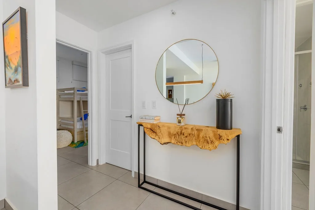 A stylish hallway accent table paired with a decorative mirror adds a welcoming touch to the space between the bedrooms.