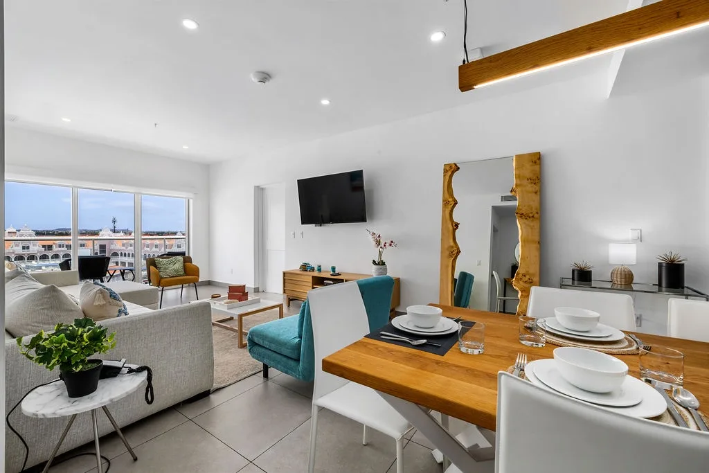 Unwind in your bright, open living space with a warm wood dining table and city views framing the windows—your perfect home base for memorable getaways.