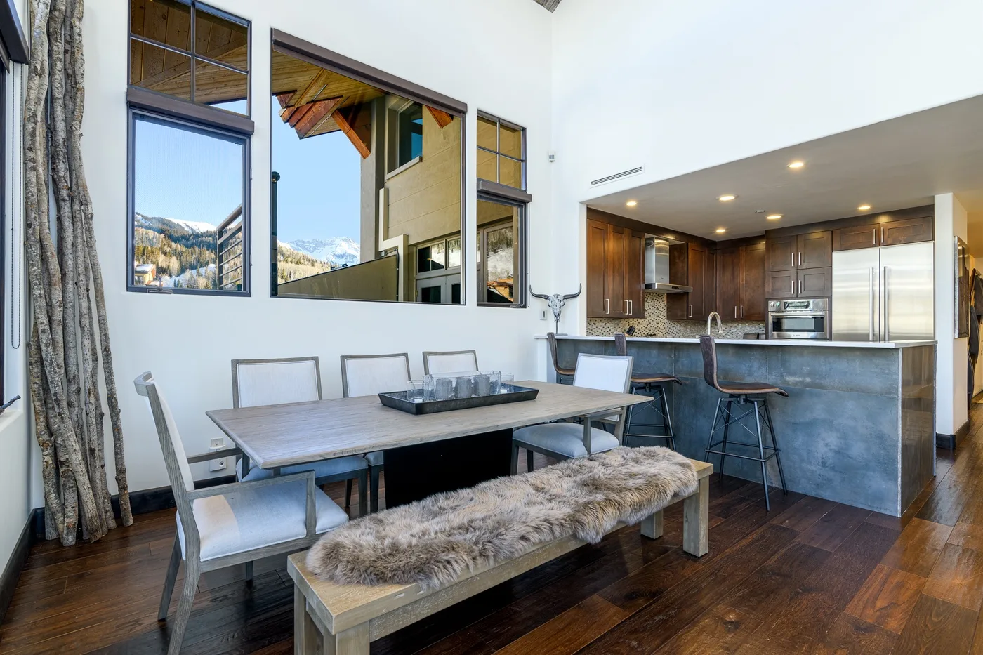 An open dining area and kitchen with a table, bench, and counter seating.