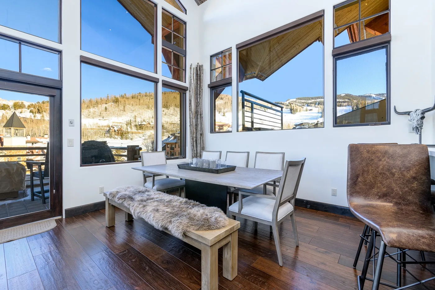 A bright dining area with a long table and large windows overlooking a snowy landscape.