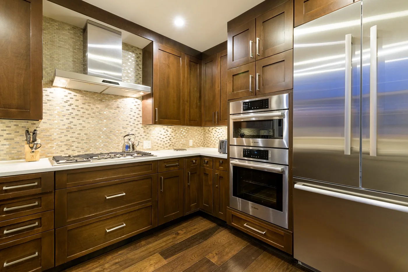 A kitchen with dark wood cabinets, stainless steel appliances, and a tiled backsplash.