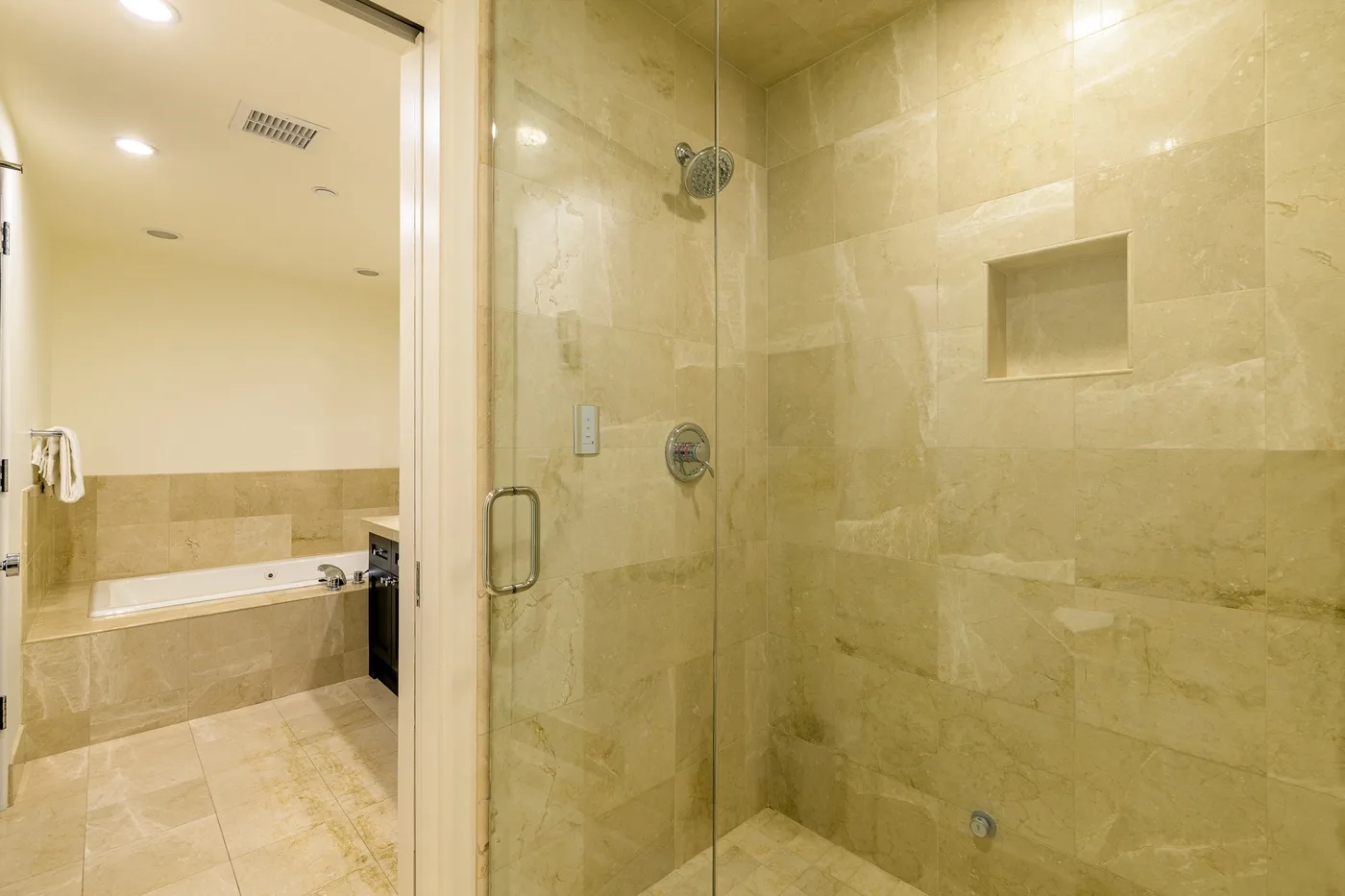 A tiled bathroom with a glass shower and a bathtub.