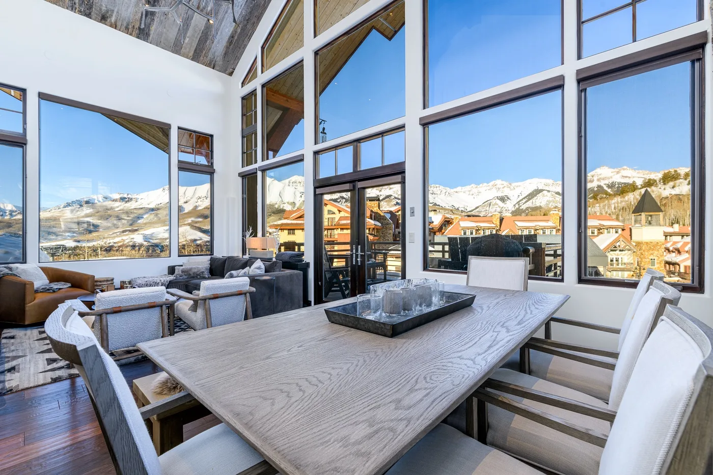A bright dining and seating area with large windows overlooking a mountain town.