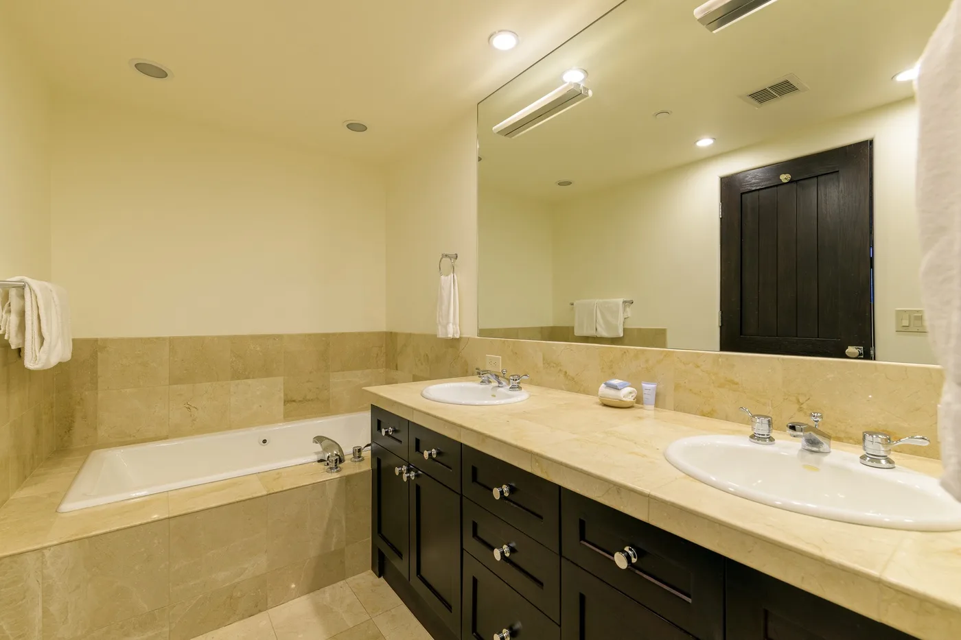 A spacious bathroom with a bathtub and a long vanity with two sinks.
