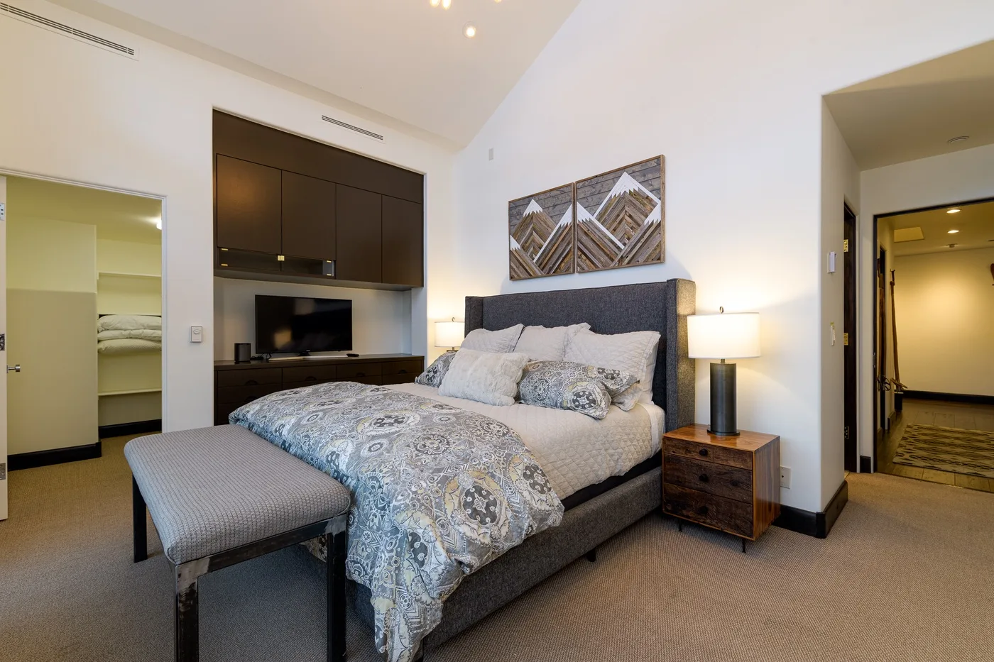 A bedroom with a large bed, patterned bedding, and matching bedside lamps.