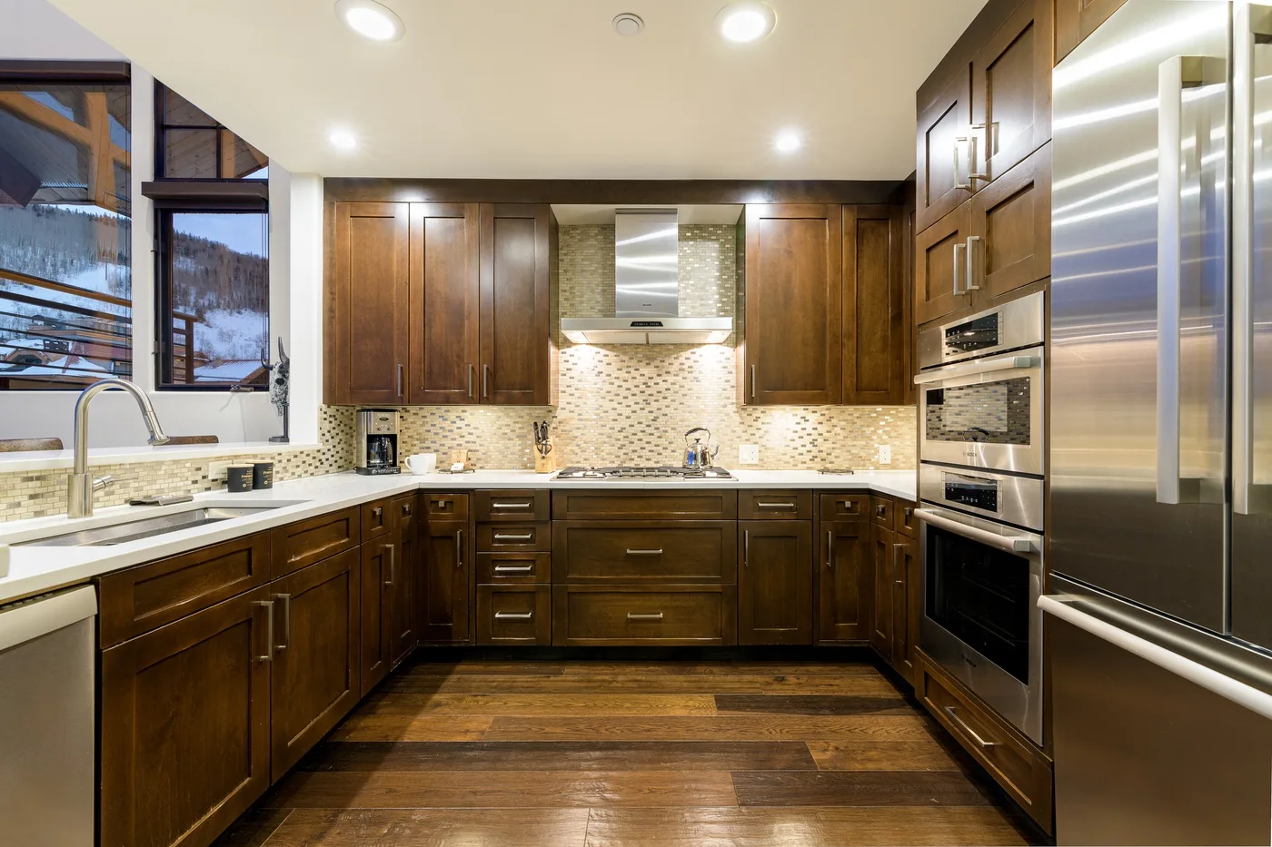 A spacious kitchen with dark wood cabinets, a central cooktop, and stainless steel appliances.