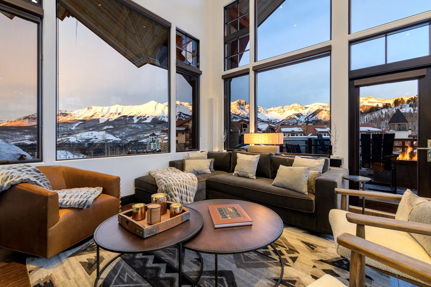 A living room with seating and large windows overlooking a snowy mountain landscape.