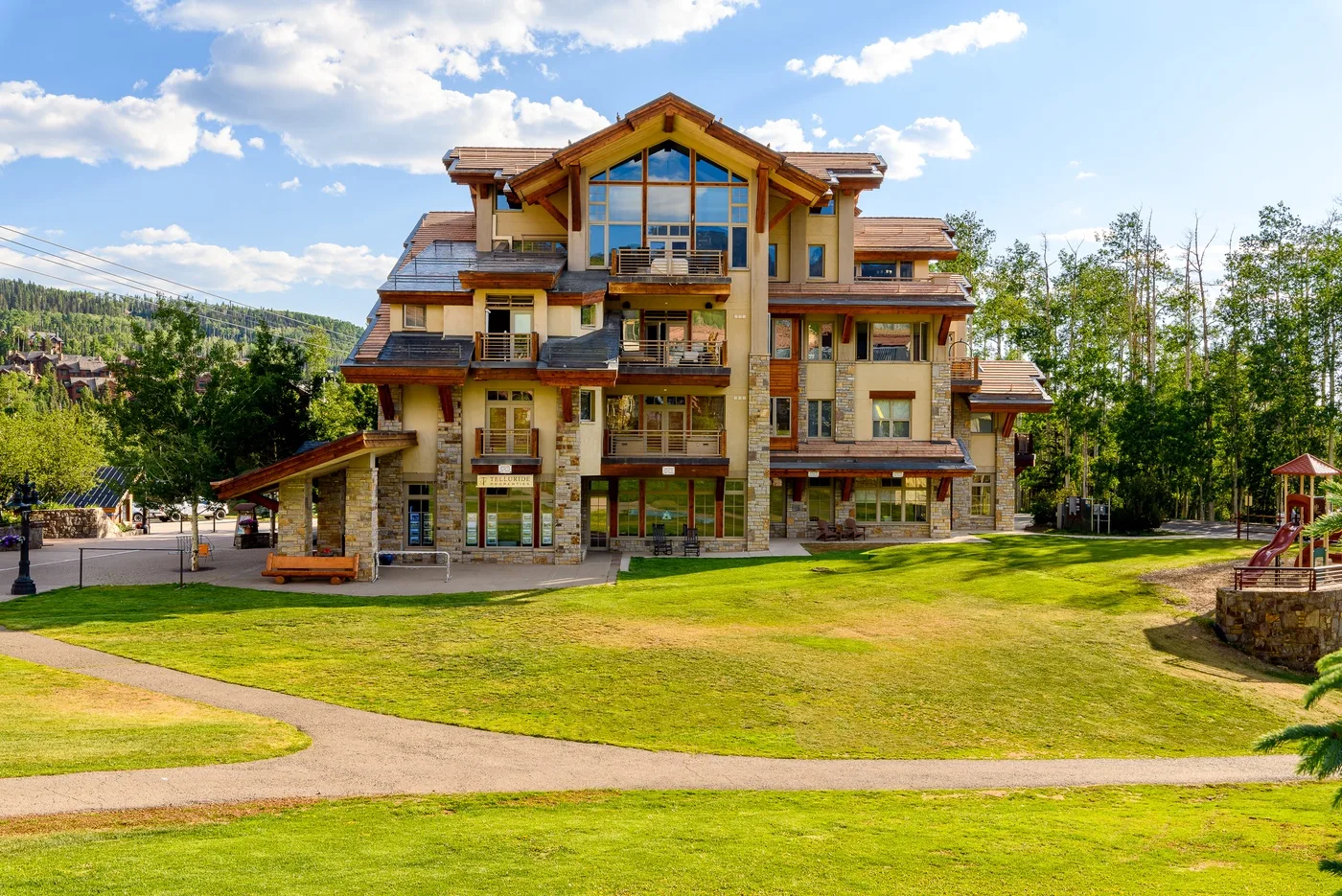 A large multi-story building stands beside a grassy lawn and paved path.
