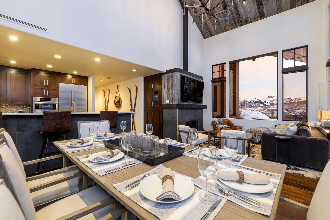 An open-plan dining and living area with a set table and mountain views.