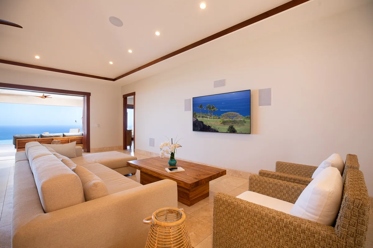 Una sala luminosa con asientos, una mesa de centro de madera y vistas al mar.