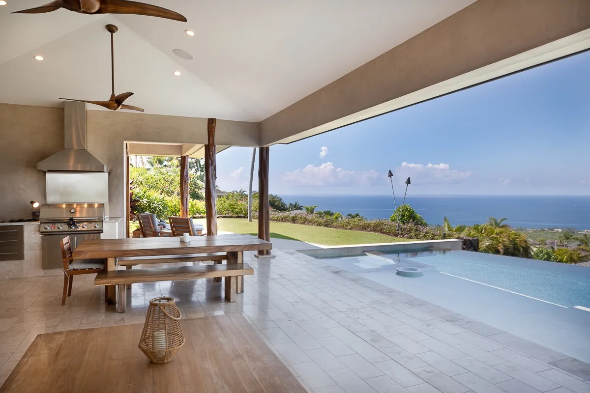 Comedor abierto junto a una piscina con vistas al mar.