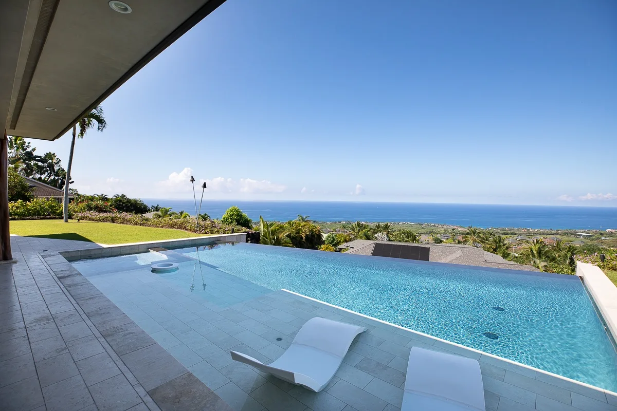 Una piscina al aire libre tiene vistas al océano y cuenta con una zona de asientos sumergida.