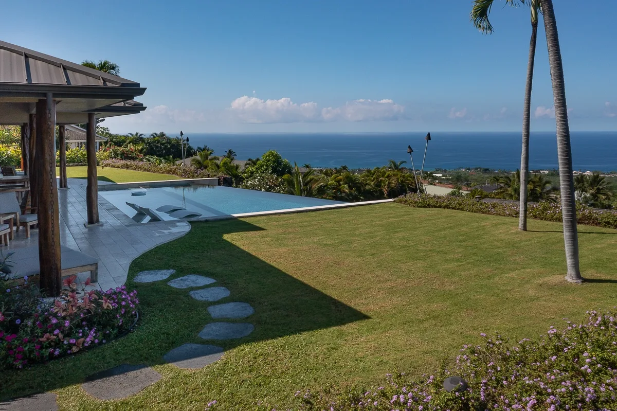 Una piscina exterior y un jardín paisajístico tienen vistas al océano.