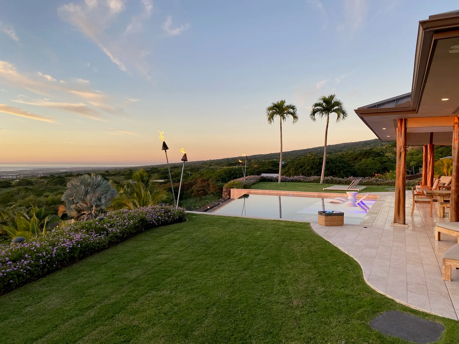 Una piscina exterior y un jardín paisajístico miran hacia las colinas al atardecer.