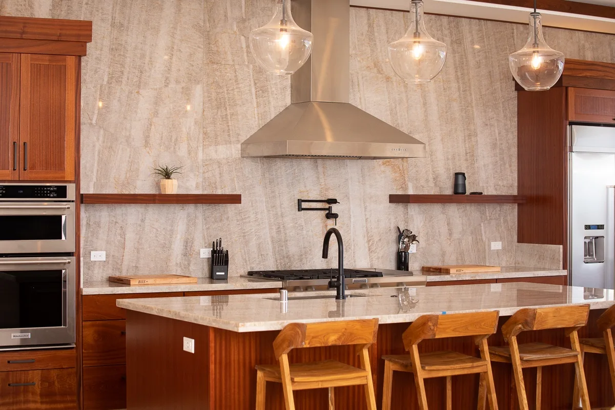 Una cocina moderna con una isla central, gabinetes de madera y luces colgantes.