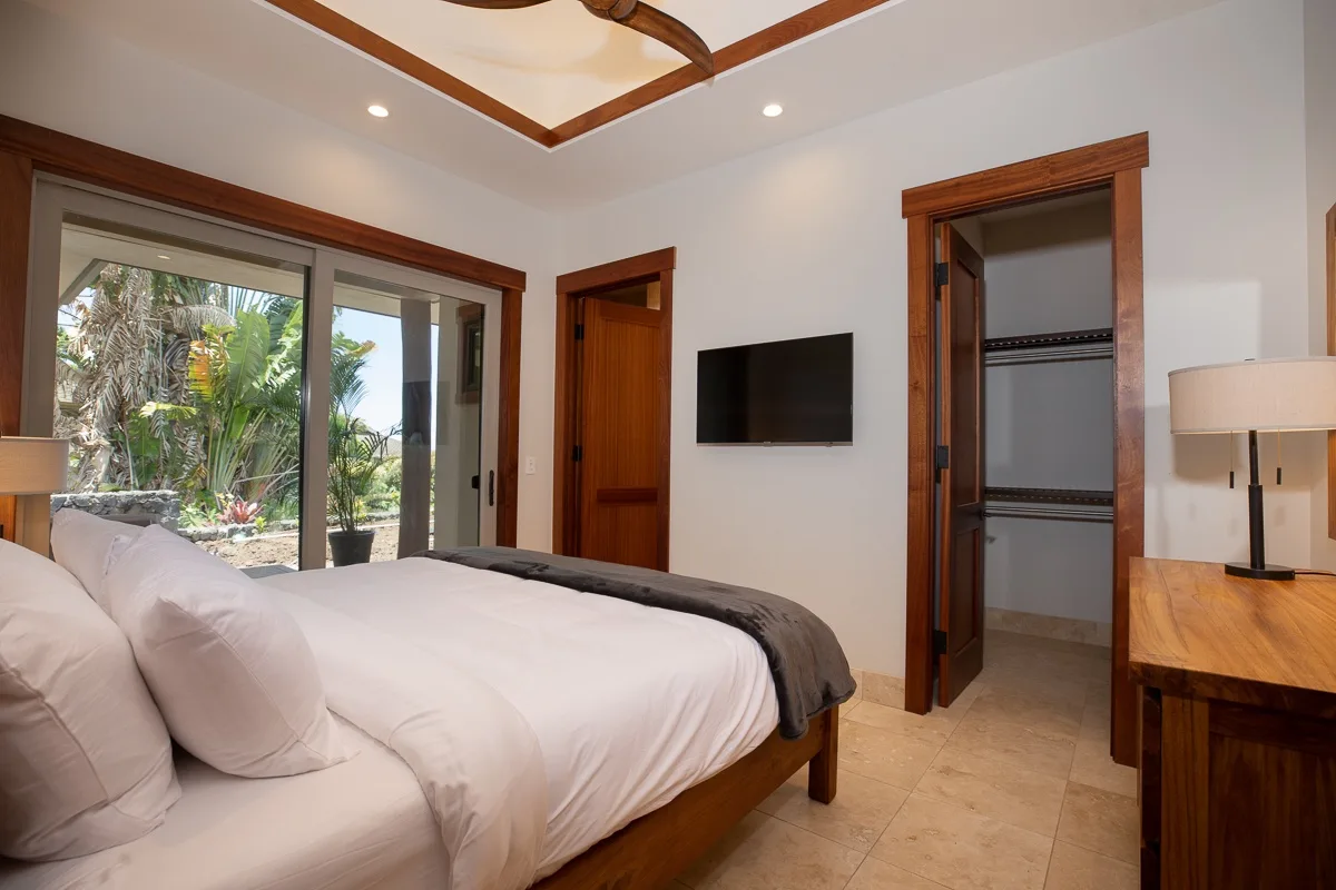 Un dormitorio con una cama, un televisor en la pared y puertas corredizas de vidrio.