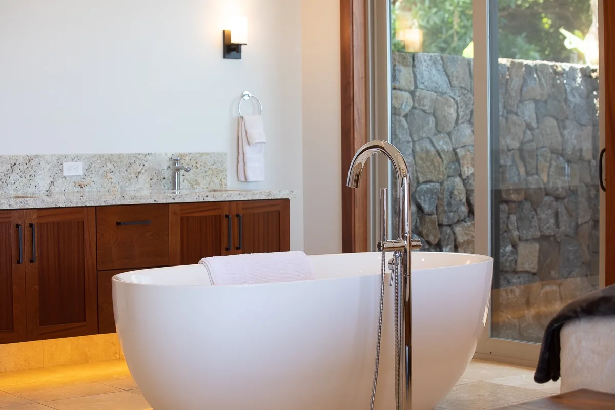 Un baño con una bañera exenta junto a una puerta grande de vidrio.