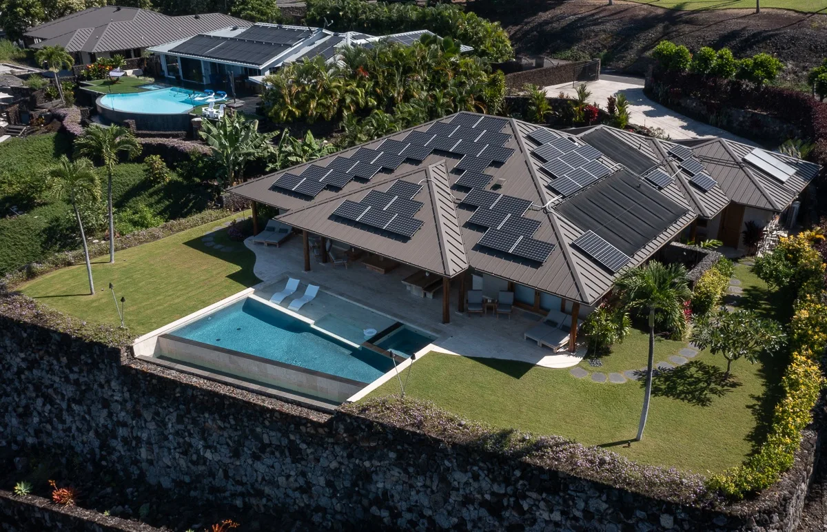 Vista aérea de una casa con paneles solares y una piscina.