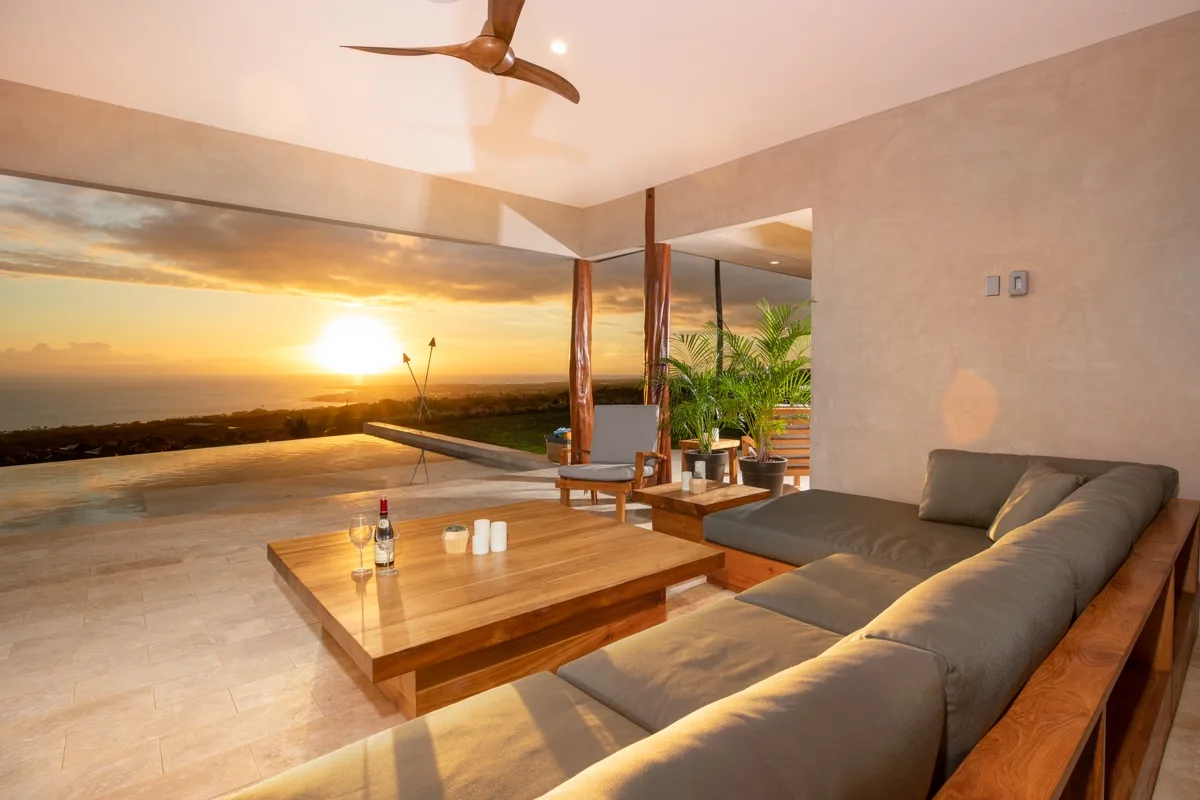 Una sala de estar se abre a una vista del atardecer, con asientos y una mesa baja de madera.
