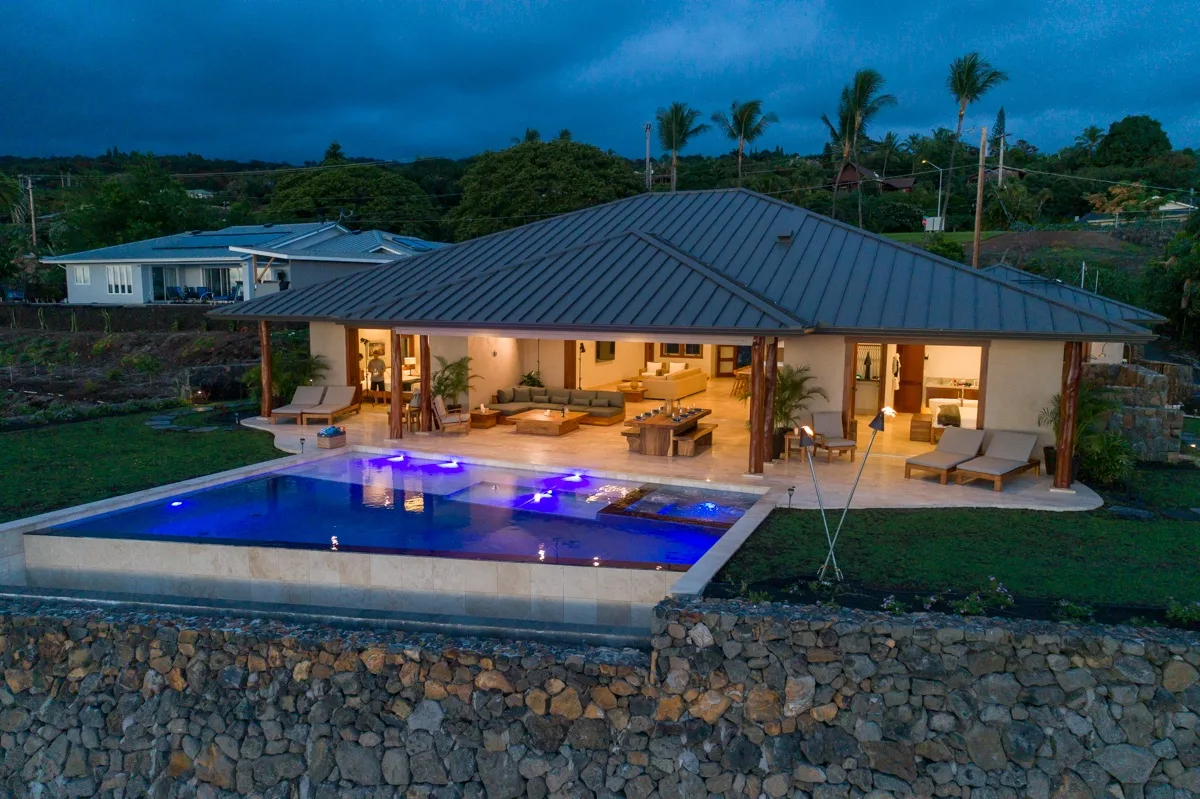 Una casa moderna da a una piscina iluminada y una zona de estar al aire libre.