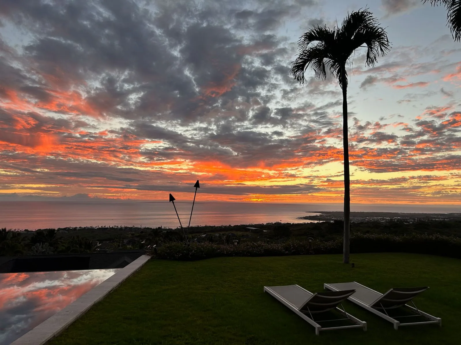 Una zona ajardinada al aire libre ofrece vistas al océano bajo un cielo de atardecer colorido.