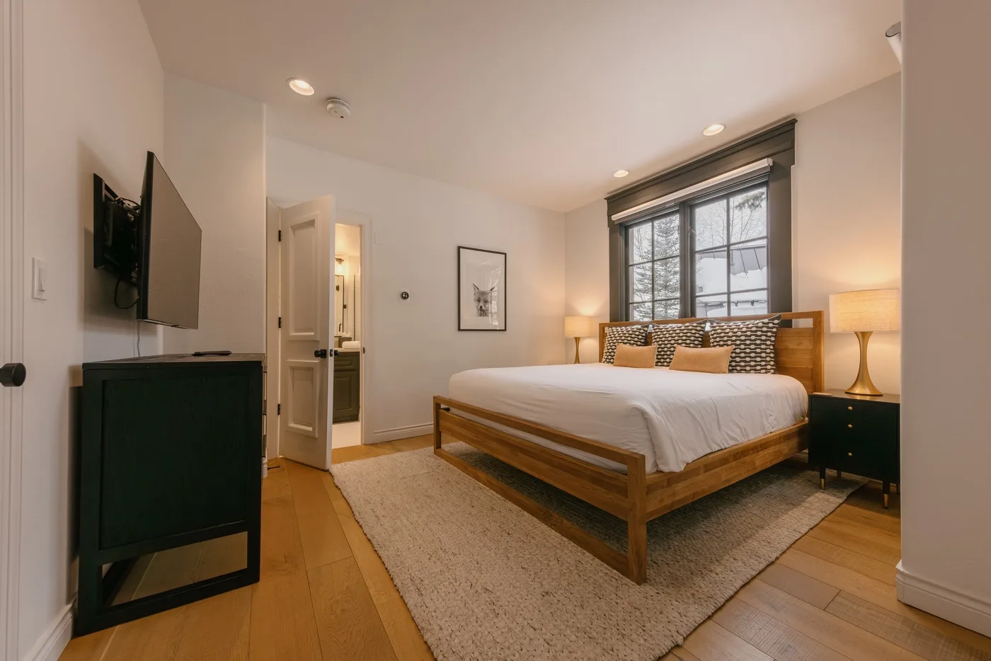 A bedroom with a wooden bed, white bedding, and a large window.