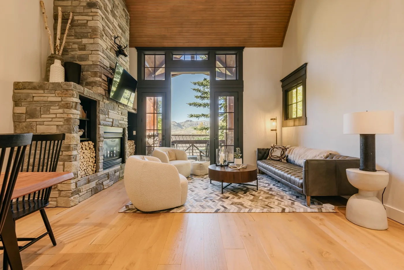 A living room with seating around a coffee table beside a stone fireplace.
