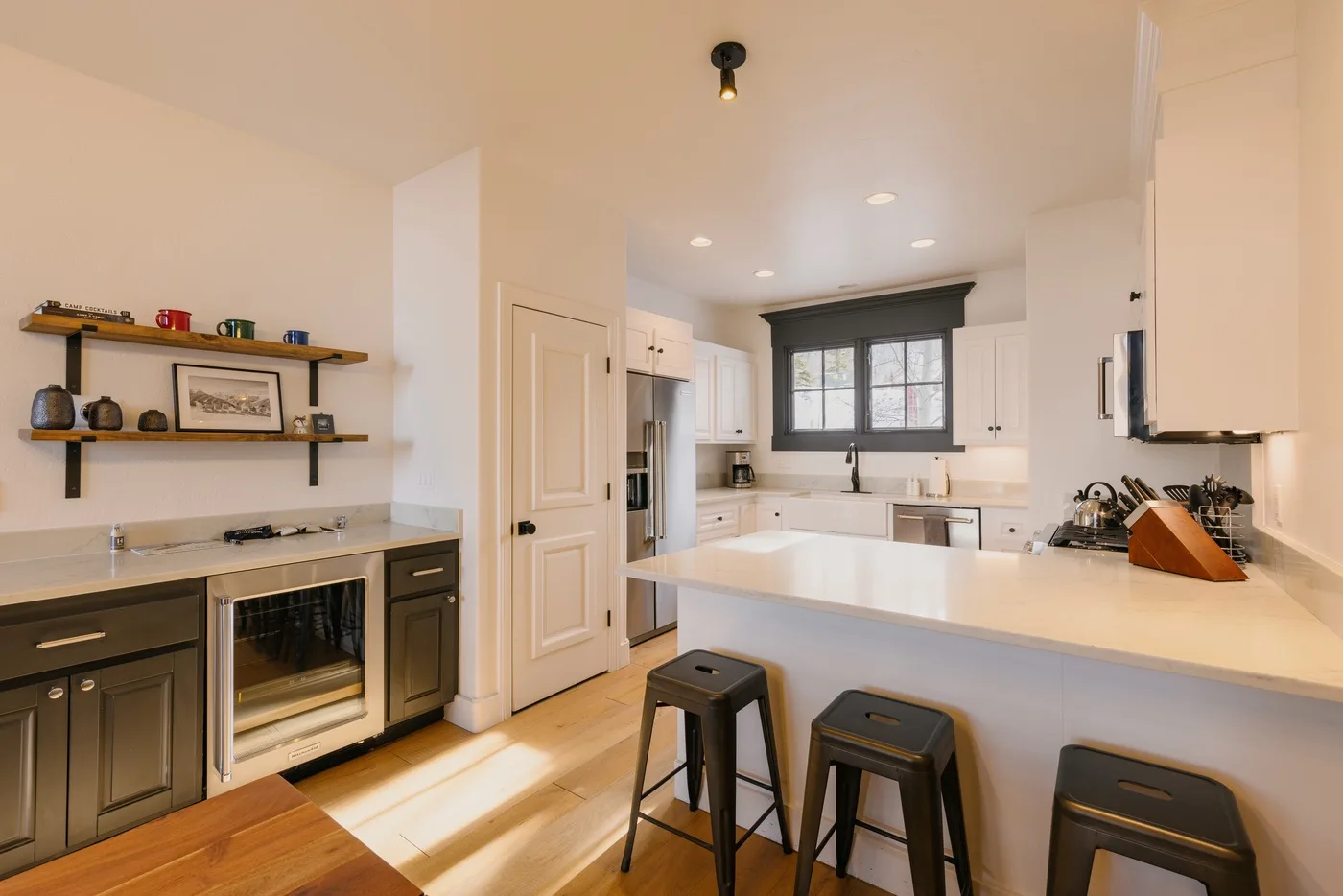 A bright kitchen with a white island, dark cabinets, and window above the sink.
