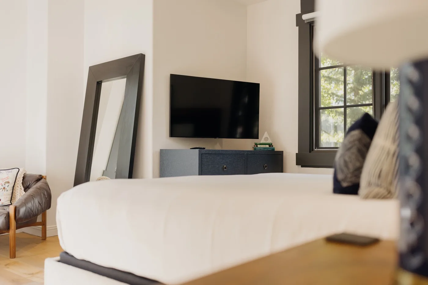 A bedroom with a bed, a television, and a window.