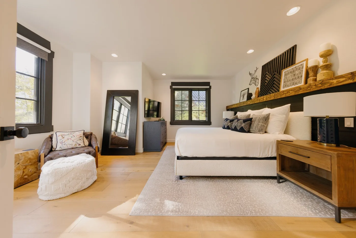 A bright bedroom with a bed, an armchair, and large windows.