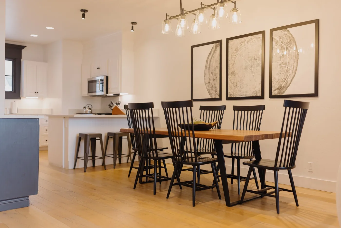 A dining area with a long wooden table, black chairs, and framed wall art.