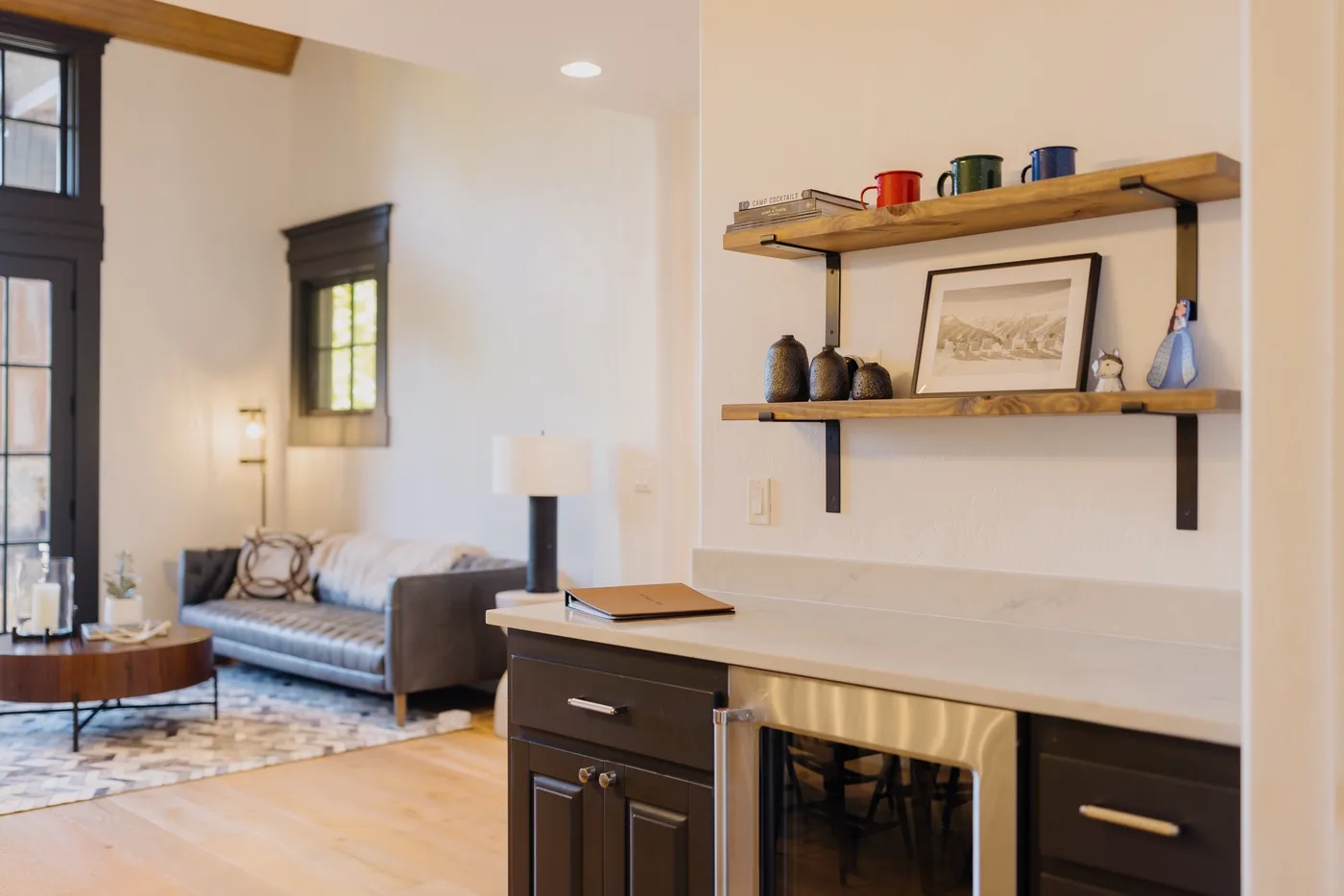 A bright living area with a sofa and a built-in desk beneath wall shelves.