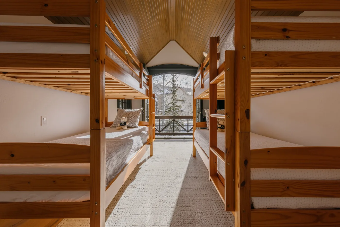 A bright sleeping area with wooden bunk beds and a window at the far end.