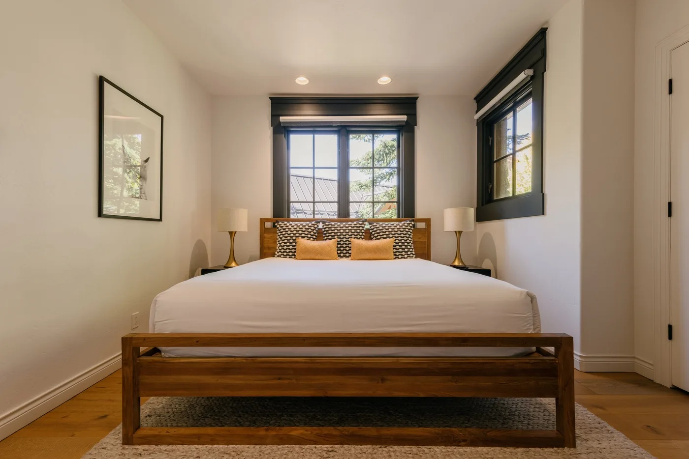 A bedroom with a wooden bed facing large windows.