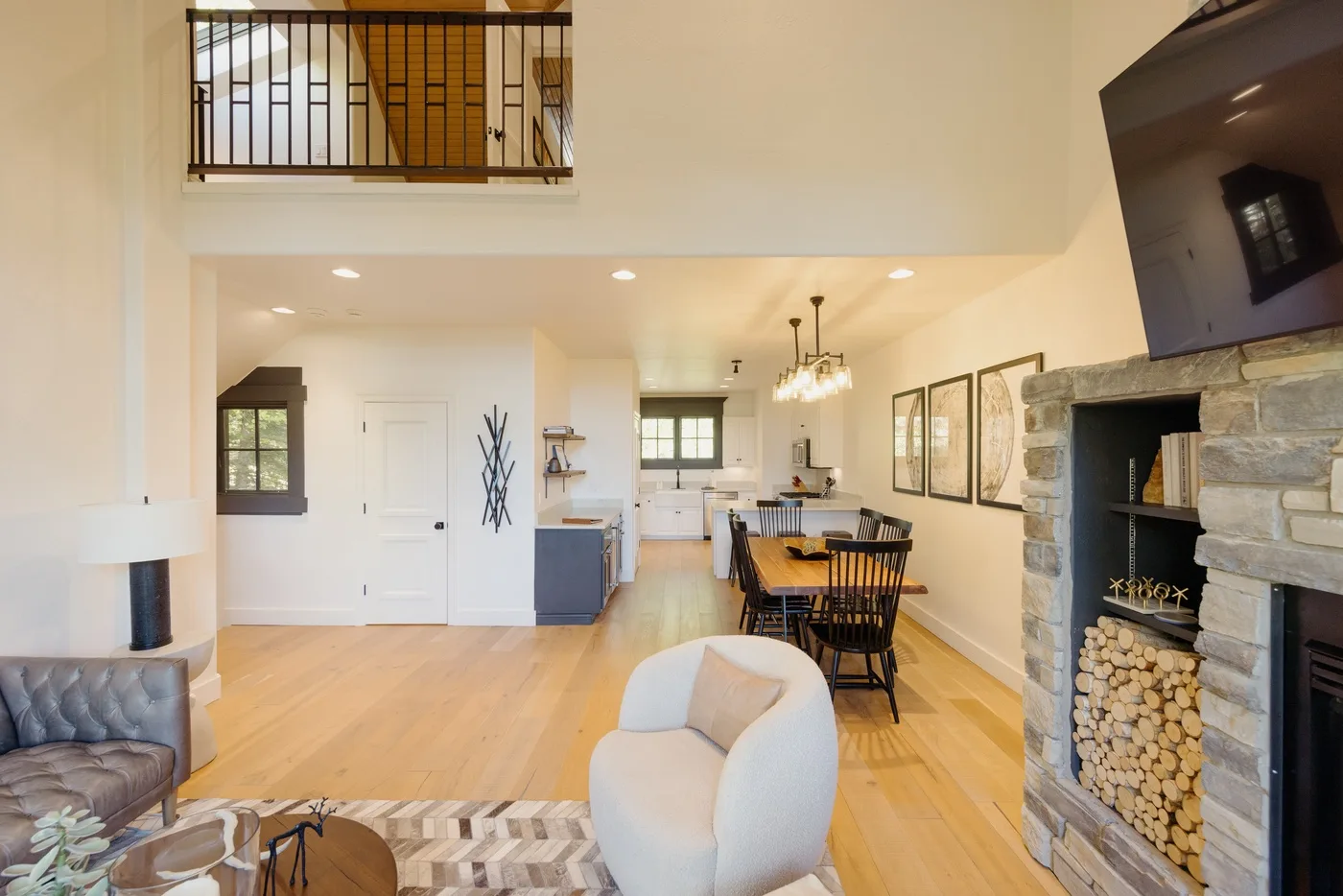 An open living and dining area with a stone fireplace and light wood flooring.
