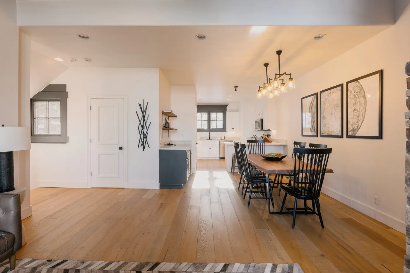 An open dining and kitchen area features a long table and dark chairs.