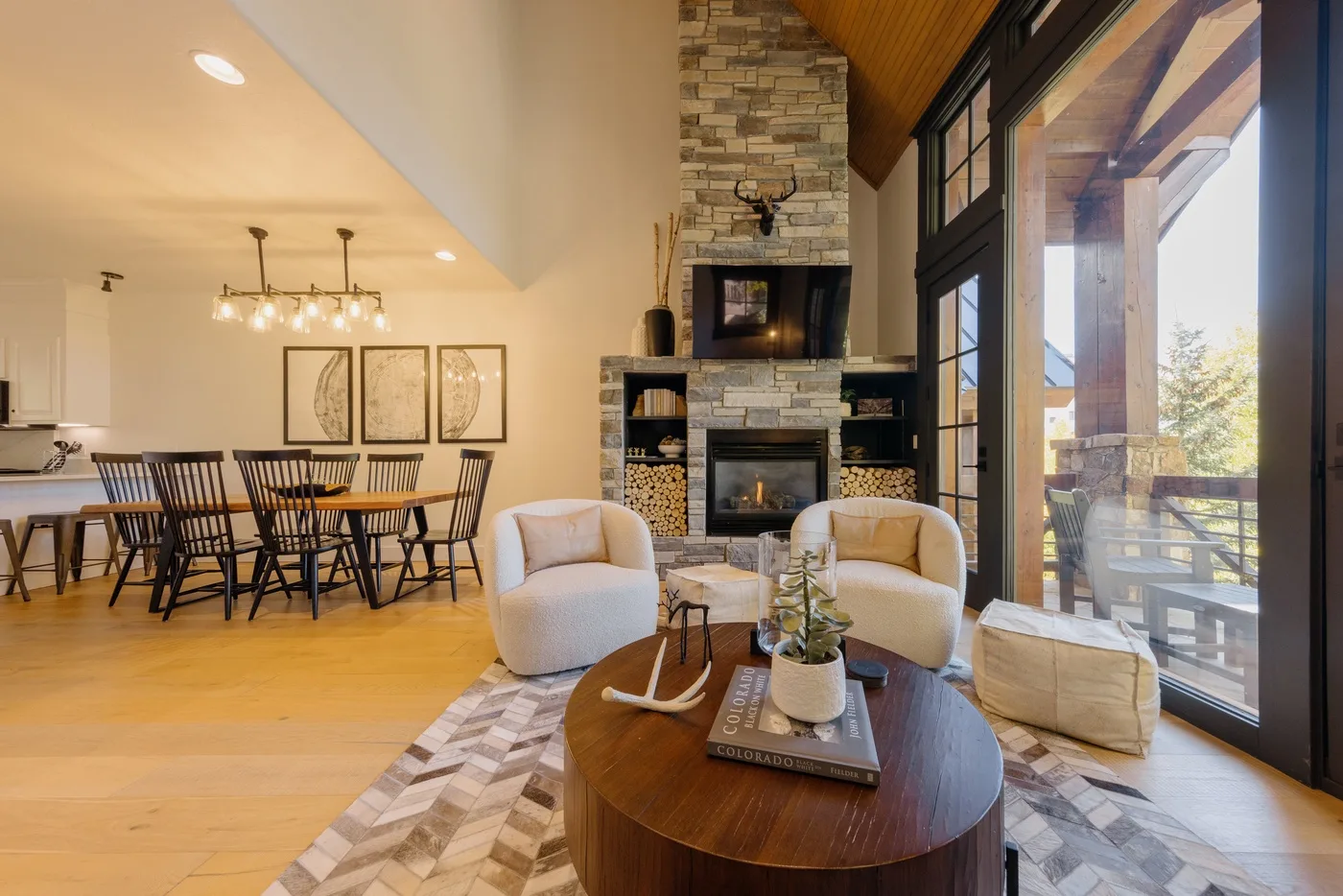 A bright open living and dining area with a fireplace and large windows.